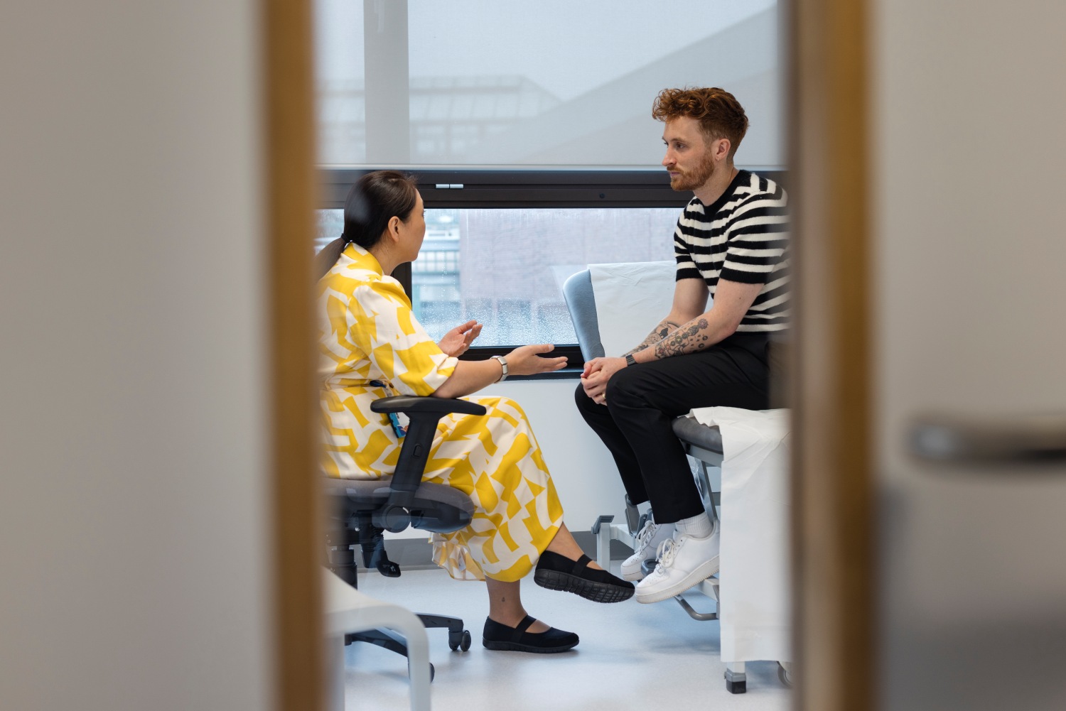 A wide angle view a young man who is visiting his GP for a consultation and some advice about an ailment.
